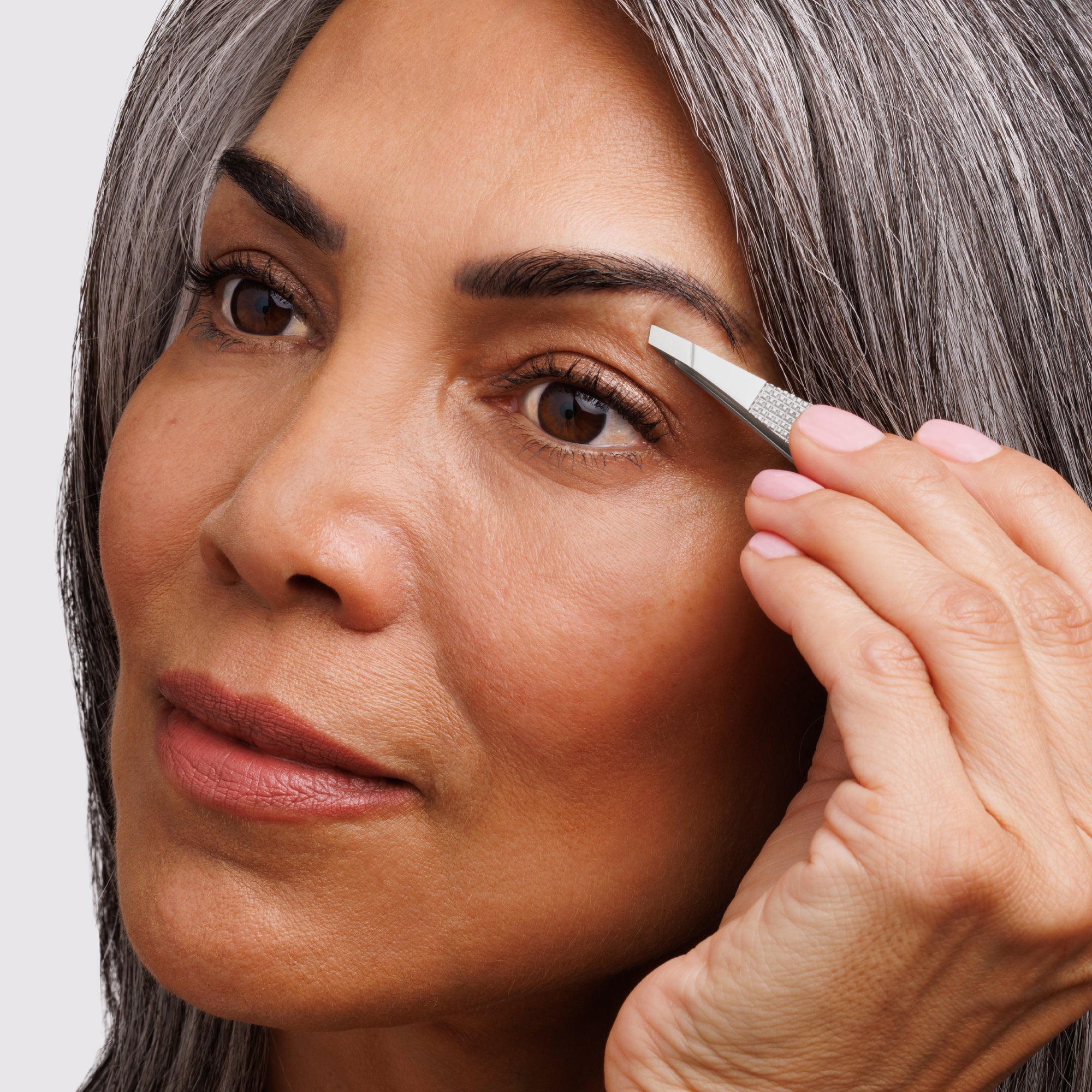 Model using the Wide Grip Slant Tweezer to tweeze brows